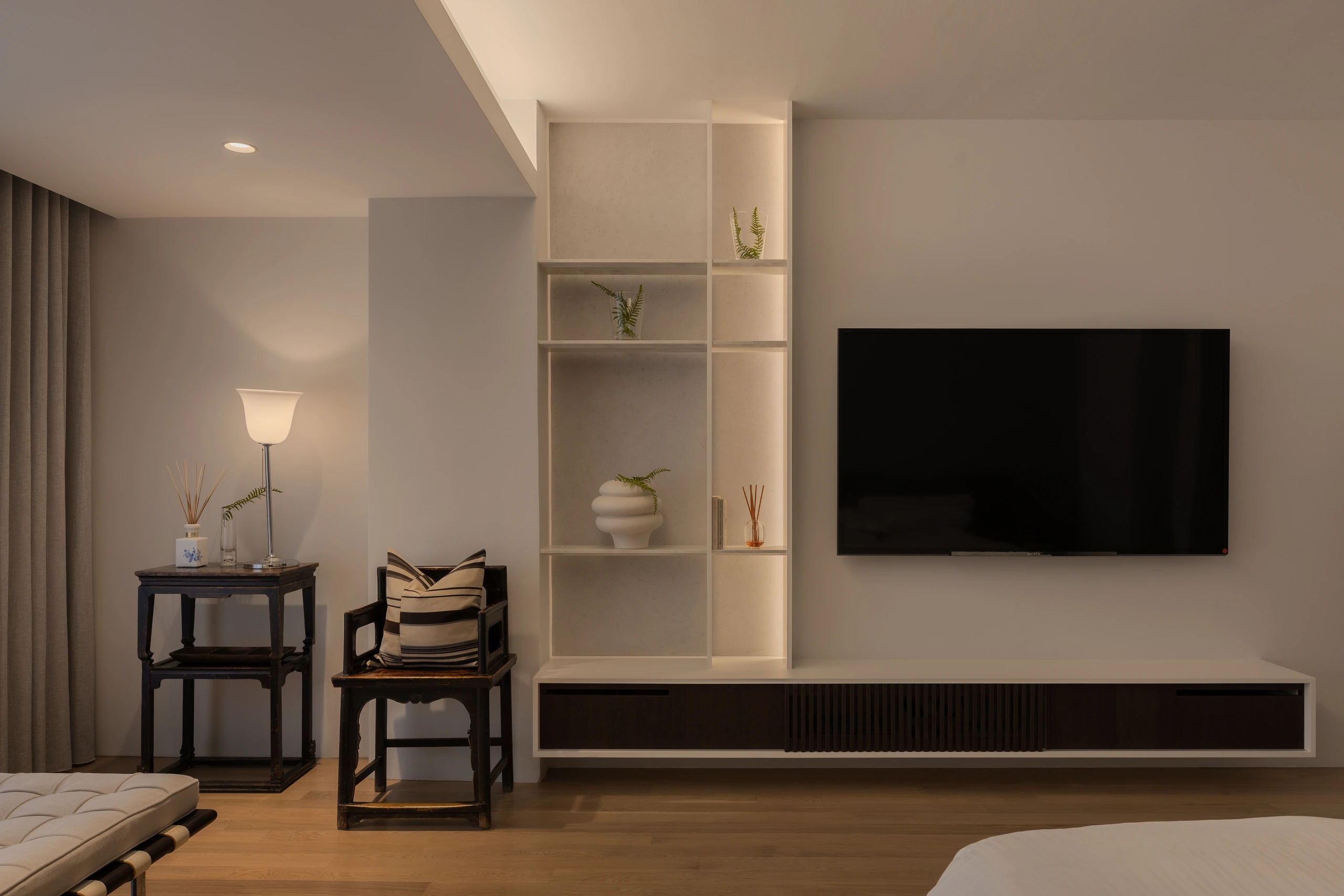 Master bedroom with timber flooring and garden-facing window by Edgeline Planners