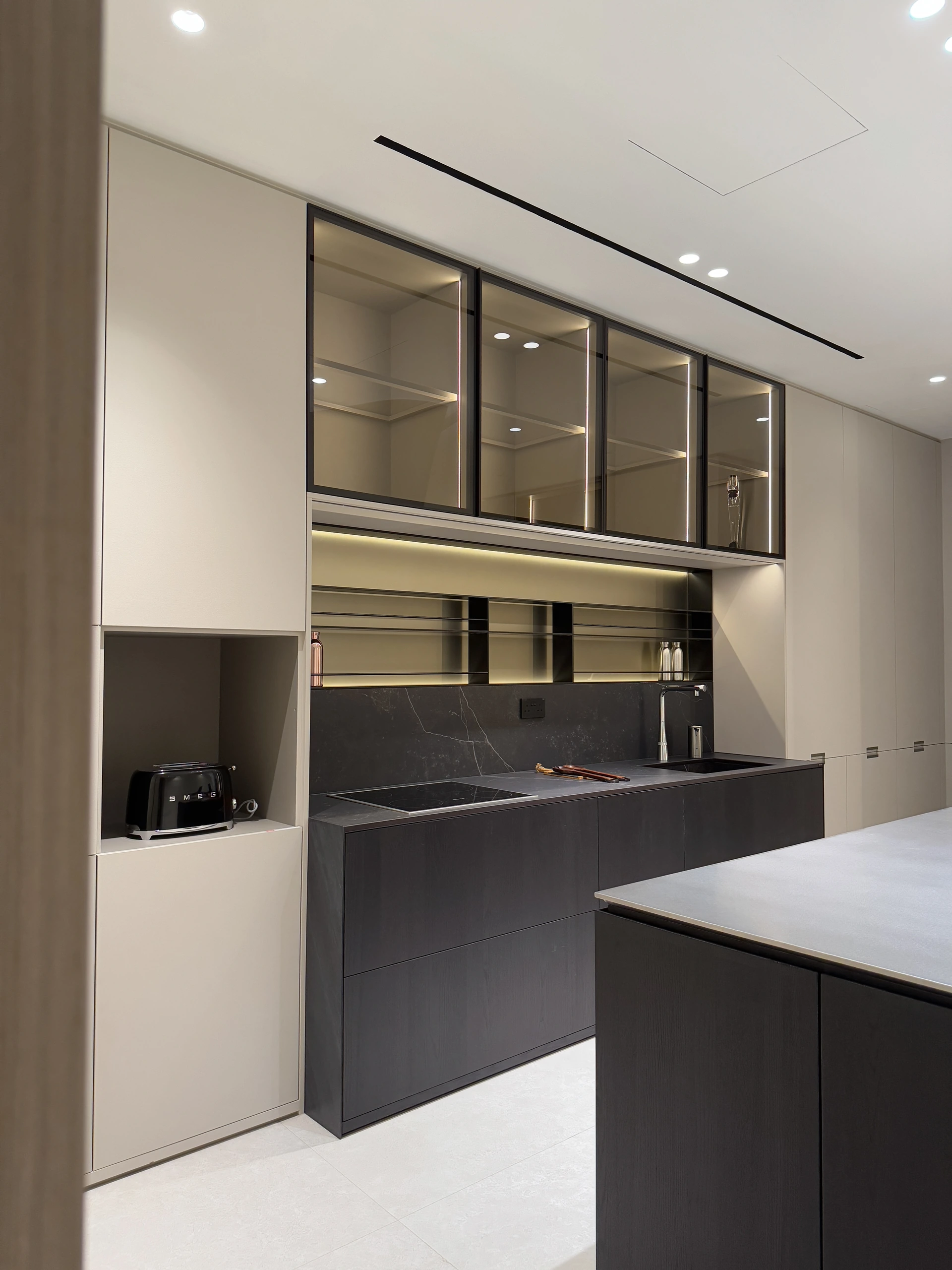 Kitchen with dark base units and pale full-height cabinetry by Edgeline Planners