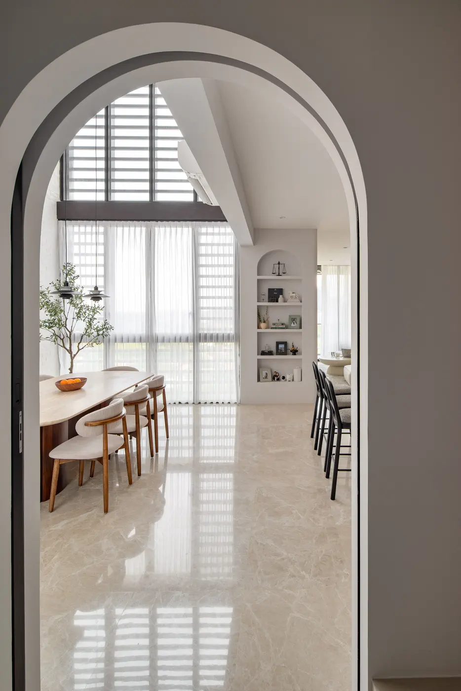 View from the arch doorway — dining area, bar counter and living room in one open sweep