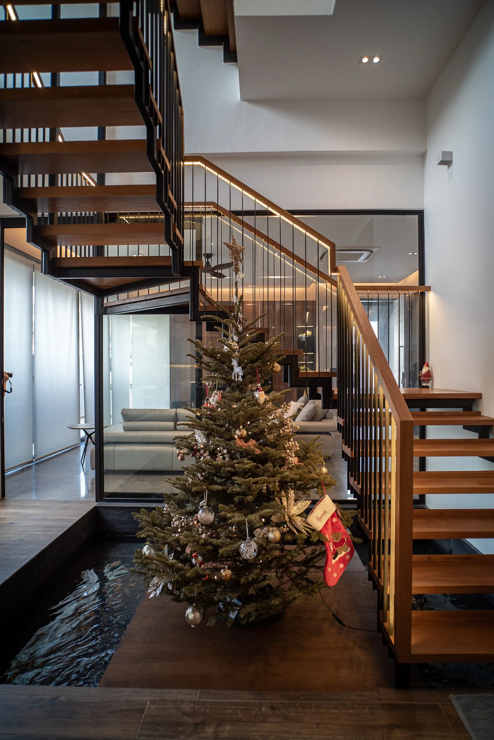 J Concept Designers &mdash; open-riser timber staircase with water feature and Christmas tree at base