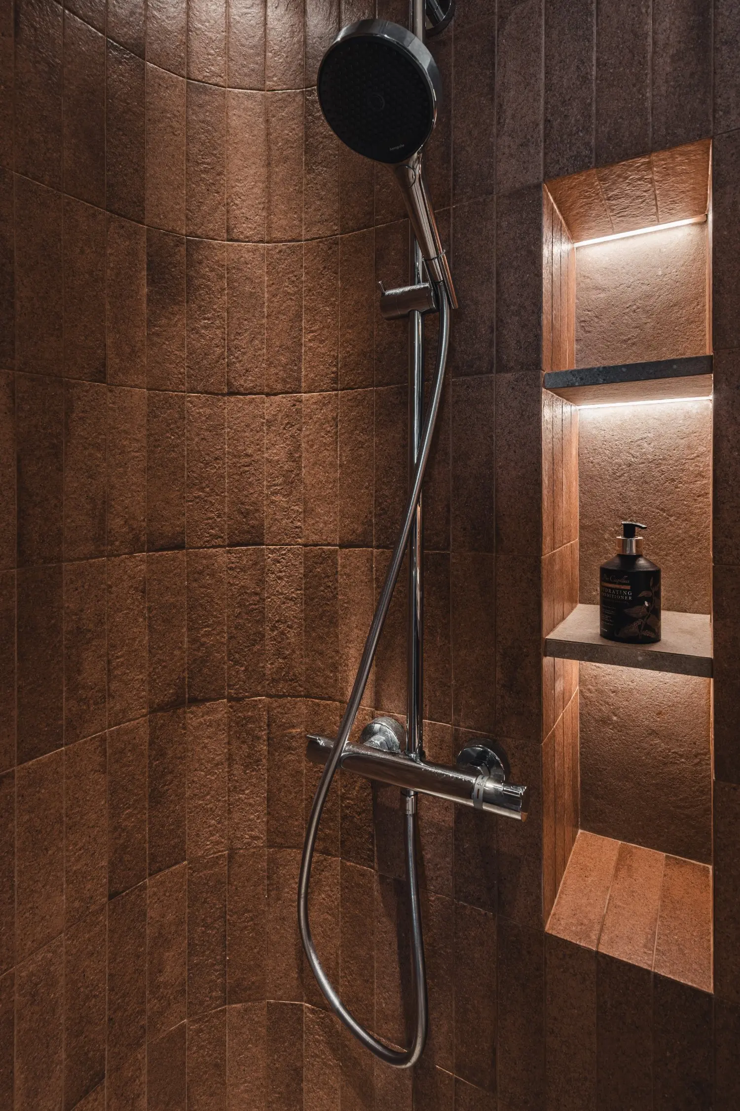 Dark tiled shower with recessed illuminated shelf