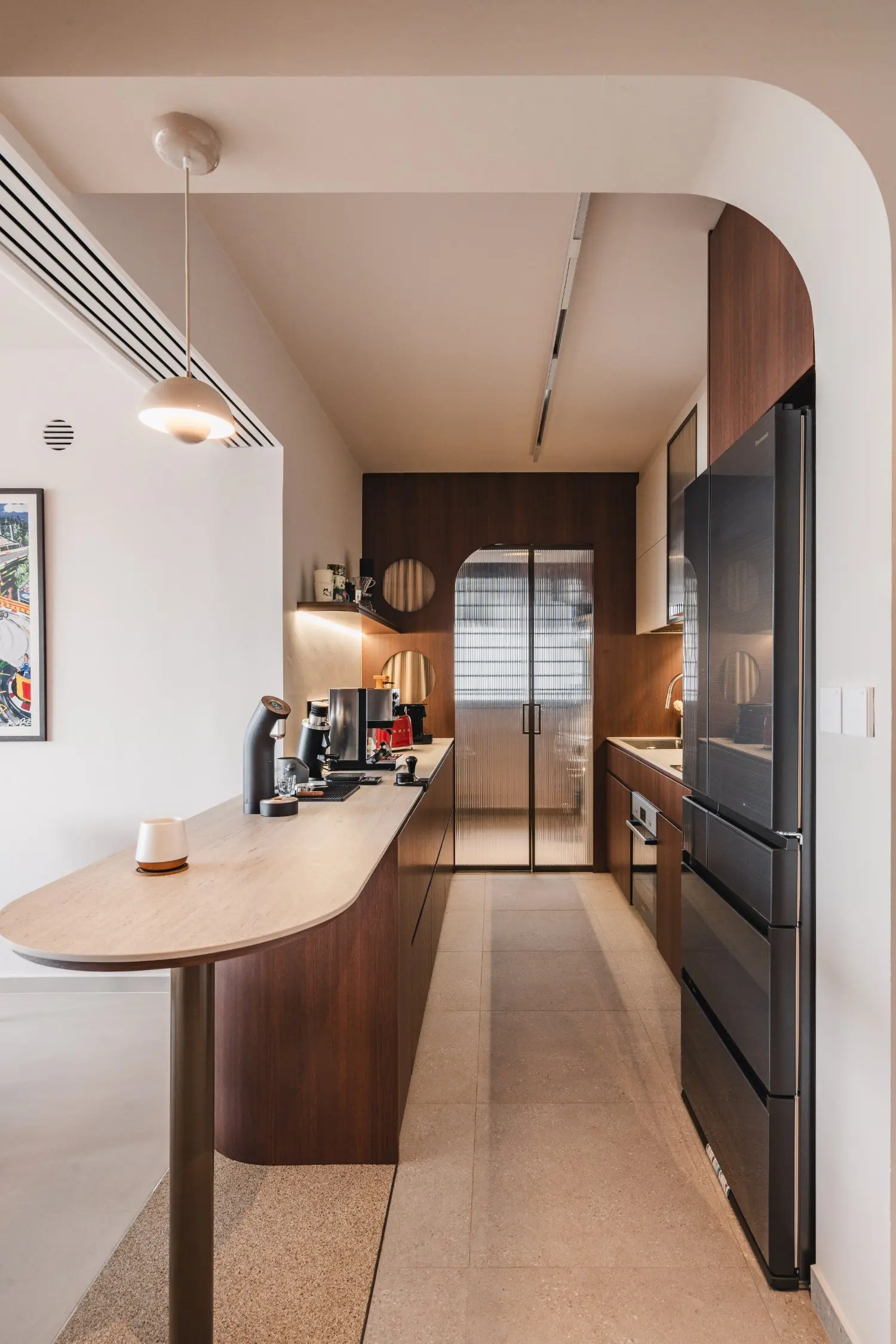 Galley kitchen with a curved peninsula, timber cabinetry and black refrigerator