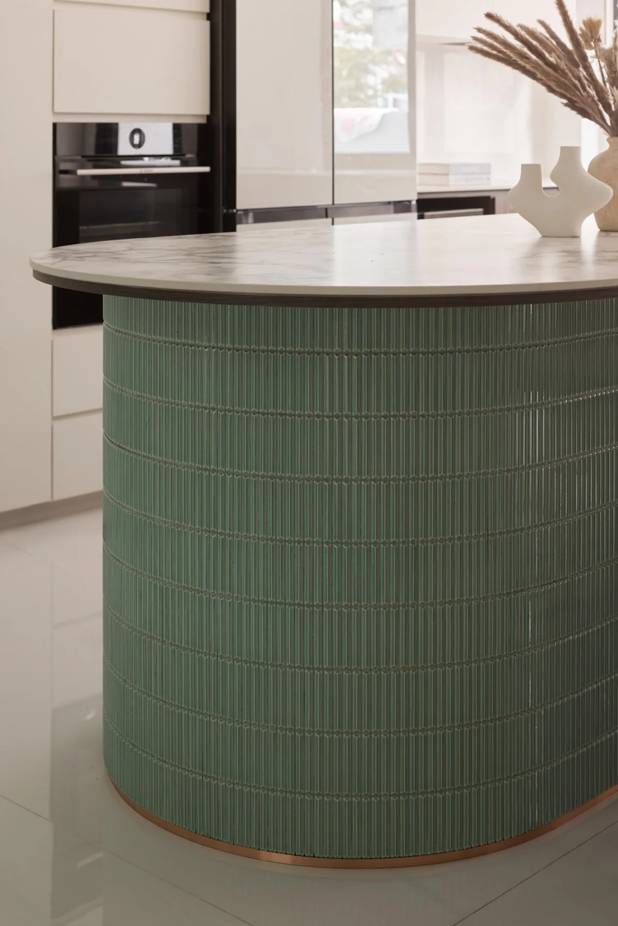 Curved kitchen island wrapped in green tiles