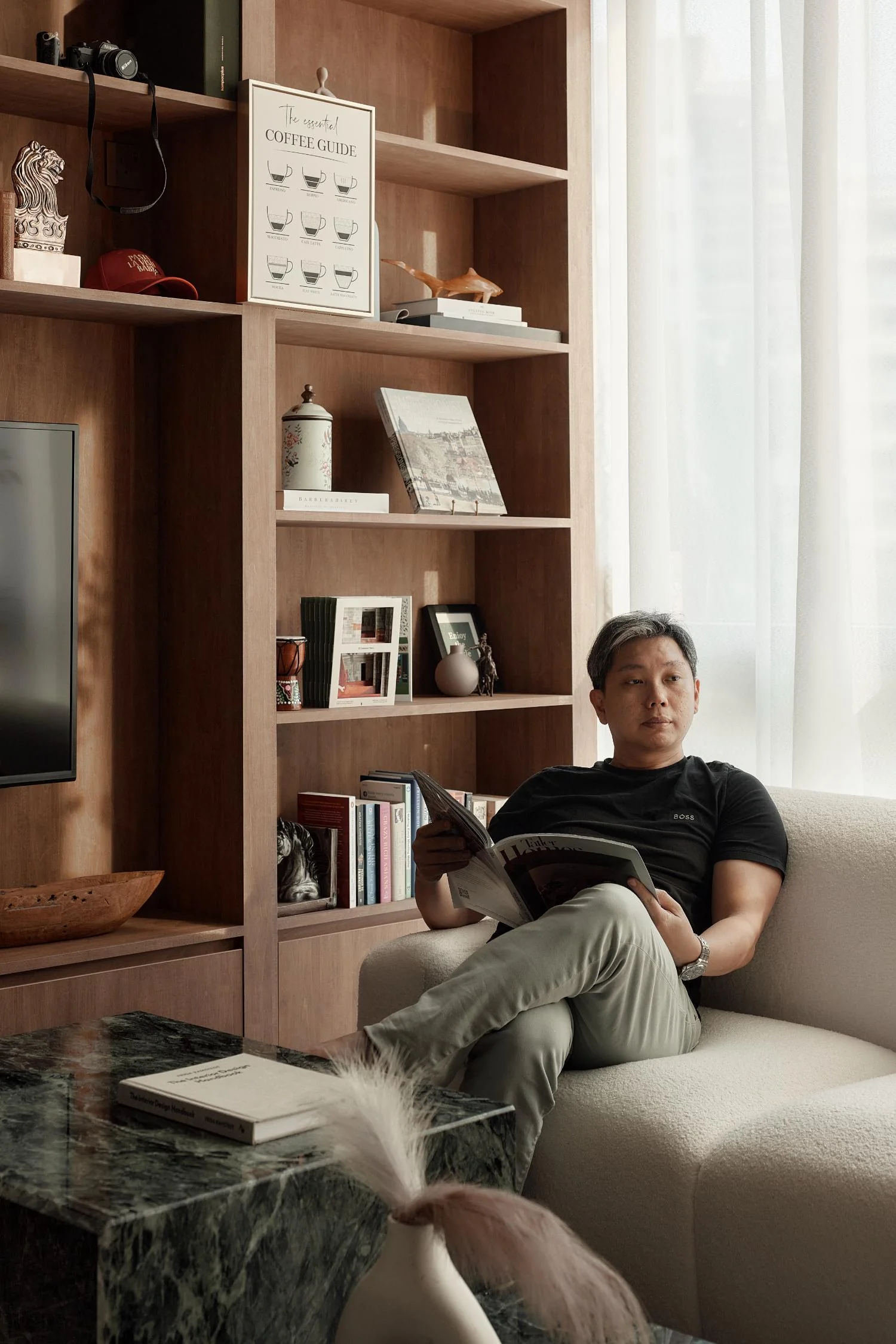 Jeremy seated beside the full-height wooden bookshelf at RENOSTUD.IO Woods Square