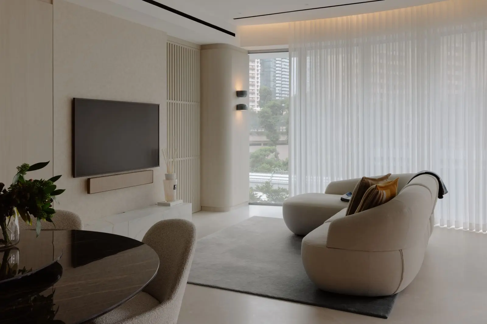 Curved sofa facing the concealed television wall and balcony windows