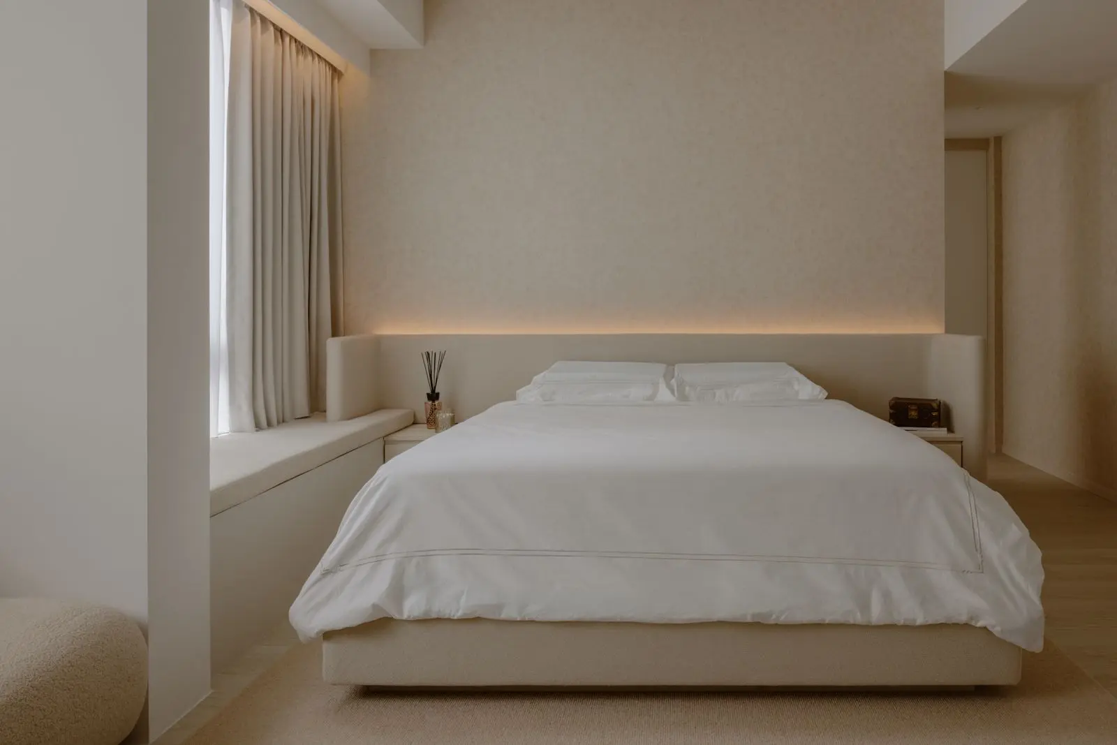 Bed set against a softly textured wall with concealed lighting